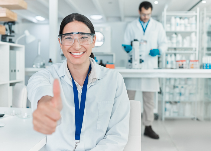 portrait of a young scientist showing thumbs up in a lab