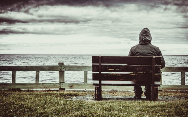man sitting on bench overlooking sea