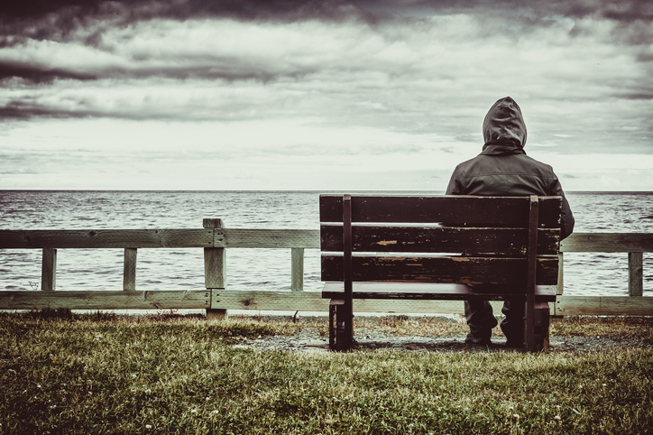 man sitting on bench overlooking sea