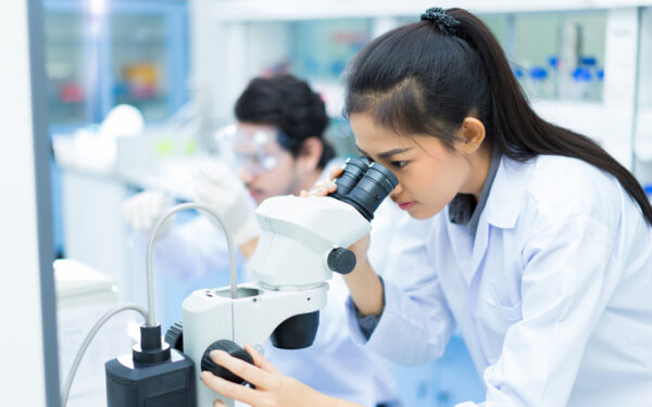 group of scientists working at the laboratory .she use microscope
