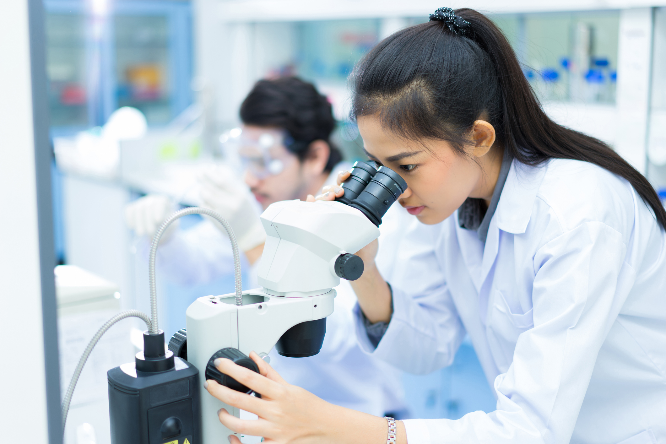 group of scientists working at the laboratory .she use microscope